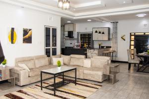 a living room with couches and a table and a kitchen at Cacecy Luxury Homes 3 Bedroom in Bungoma