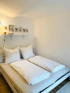 1 cama con sábanas blancas y almohadas en una habitación en Terrassenwohnung mit Donaublick, en Obernzell