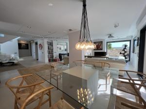 comedor y sala de estar con mesa de cristal y sillas en Preciosa Villa en Siesta en Santa Eulalia del Río
