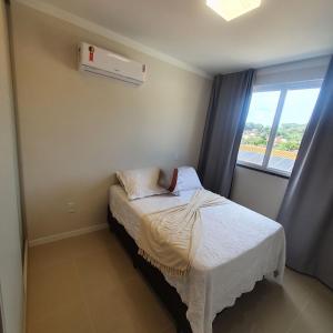a small bed in a room with a window at Apartamento de Luxo com Piscina em Bombinhas in Bombinhas