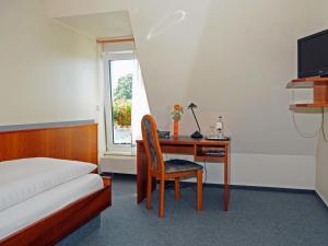 1 dormitorio con escritorio, 1 cama, 1 cama, escritorio y silla en Hotel-Restaurant Thomsen, en Delmenhorst