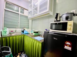 a kitchen with a microwave on top of a refrigerator at Izdisa Muslim Homestay Teluk Kemang Groundfloor unit with Pool view in Port Dickson