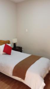 ein Schlafzimmer mit einem Bett mit einem roten Kissen darauf in der Unterkunft Runcu Arequipa in Arequipa
