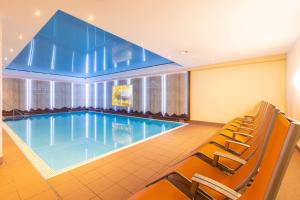 ein großer Pool mit Stühlen in einem Hotelzimmer in der Unterkunft IFA Alpenrose Hotel Kleinwalsertal in Mittelberg
