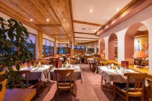 un restaurante con mesas, sillas y ventanas en IFA Alpenrose Hotel Kleinwalsertal en Mittelberg