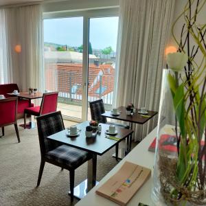 een hotelkamer met tafels en stoelen en een groot raam bij IBB Hotel Ingelheim in Ingelheim am Rhein