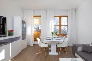 uma sala de estar branca com uma mesa e cadeiras em Rynek Sienny Cosy Apartment em Szczecin