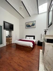 a bedroom with a bed and a flat screen tv at Hotel Alhaja in Puebla