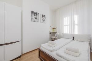 um quarto branco com uma cama grande e lençóis brancos em Rynek Sienny Cosy Apartment em Szczecin