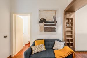 ein Wohnzimmer mit einer blauen Couch mit Kissen in der Unterkunft Kibilù - Via dell'Unione - City Centre - Duomo in Mailand