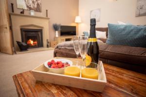 a bottle of wine and a bowl of fruit on a table at Purves Cottage in Allanton
