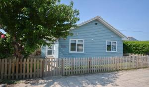 une maison bleue avec une clôture devant elle dans l'établissement Swallows Croyde - Open plan beach chalet & close proximity to the beach - Sleeps 6, à Croyde