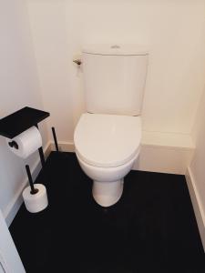 La salle de bains est pourvue de toilettes blanches et d'un sol noir. dans l'établissement Chambre privée Au pied des Vosges, à Remiremont