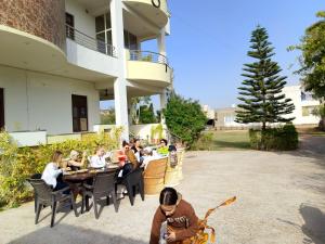 Hotel Divine Palace Pushkar في بوشكار: مجموعة من الناس يجلسون في مطعم خارجي