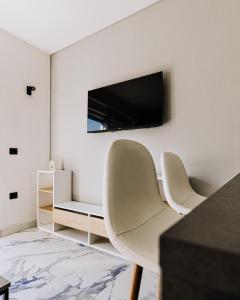 a living room with two chairs and a tv on the wall at Allegra House in Zagreb