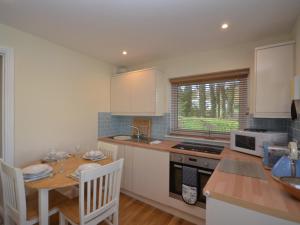 uma cozinha com armários brancos, uma mesa e um micro-ondas em 2 Bed in Brixham BX054 em Brixham