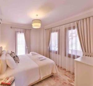 Un dormitorio con una cama blanca y dos ventanas. en Zahna Apartment, en Kas