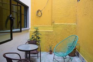 uma mesa e cadeiras sentadas ao lado de uma parede amarela em Casa Miranda Morelos em Guadalajara