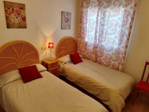 1 dormitorio con 2 camas y cortina roja en San Miguel, en Membrilla