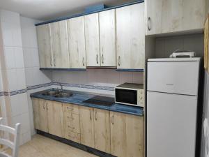 una cucina con armadi in legno e frigorifero bianco di San Miguel a Membrilla