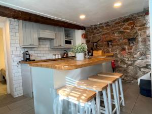 a kitchen with a counter and stools in a room at Boatsman's Cottage- sleeps 4- Garage- Mousehole in Mousehole