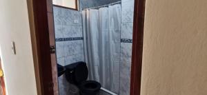 La salle de bains est pourvue d'une douche avec rideau de douche blanc. dans l'établissement HOSTAL EL REFUGIO, à Huanchaco