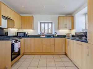 a kitchen with wooden cabinets and a sink at 4 Bed in Taunton KIBTR in Trull