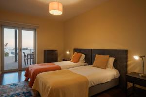two beds in a room with a balcony at Casa dos Ciprestes in Ericeira