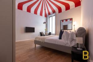 a bedroom with a bed with a red and white canopy at BePlace Apartments in Chinatown in Milan