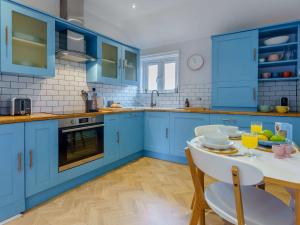 kuchnia z niebieskimi szafkami i stołem z krzesłami w obiekcie 2 bed property in Rye 87139 w mieście Rye