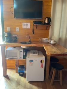 a kitchen with a table with a sink and a microwave at Pousada rio canoas in Urubici