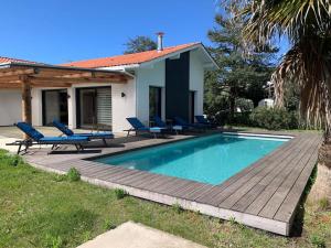 een huis met een zwembad en blauwe ligstoelen bij Villa proche océan et golf in Anglet