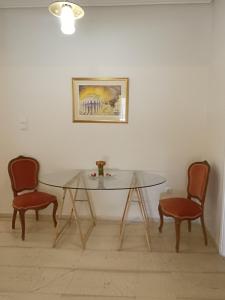 uma mesa de vidro e duas cadeiras num quarto em Your Athens home em Atenas