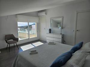 een slaapkamer met een bed, een stoel en een raam bij FANTÁSTICO DÚPLEX CON VISTAS IMPRESIONANTES AL MAR in Peñíscola