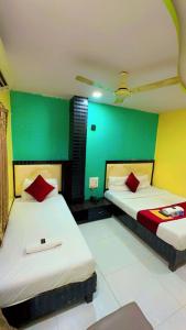 two beds in a room with green and yellow walls at Hotel Avenue Regency in Mumbai
