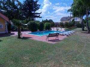 a swimming pool with a bench and chairs in a yard at Éden Villa Apartmanház 2 in Balatonfüred