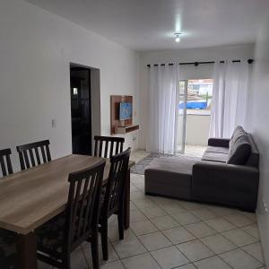 ein Wohnzimmer mit einem Tisch und einem Sofa in der Unterkunft Apartamento 102 mobiliado 2 quartos Jaraguá do Sul-SC in Jaraguá do Sul