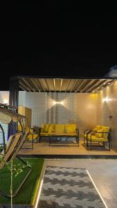 a patio with yellow chairs and a couch on a deck at شاليه الرتيل in Ash Shuwaybiţ