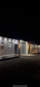 a white house with a garage at night at شاليه الرتيل in Ash Shuwaybiţ