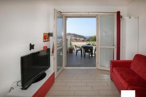 ein Wohnzimmer mit einem TV und einer roten Couch in der Unterkunft Vacanze da Favola in Castelsardo