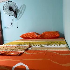 a bed with an orange comforter and a fan at HOTEL casa VALLENATA in Valledupar