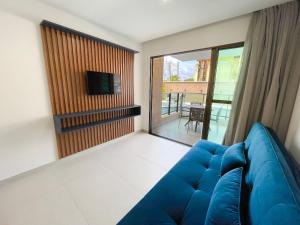 ein Wohnzimmer mit einem blauen Sofa und einem TV in der Unterkunft Tangaroa #01 em Porto de Galinhas por Carpediem in Porto De Galinhas