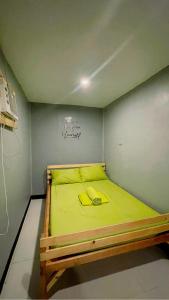 um pequeno quarto com uma cama com lençóis amarelos em Mantilla Hostel em Coron