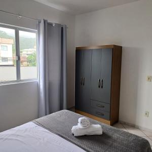 a bedroom with a bed and a cabinet with towels on it at Apto 102 Figueira Parque - Mobiliado 2 quartos in Jaraguá do Sul