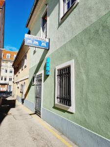 un edificio verde con un cartel en el costado en Adamas, en Celje