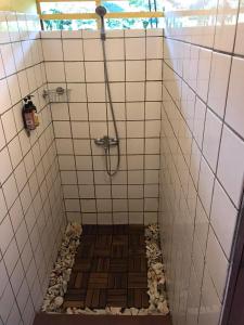 a bathroom with a shower with a tiled floor at My Island Home in Fare