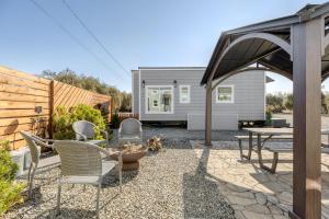 a patio with chairs and a table in a backyard at Red Door Tiny Home Lewis Ranch in Lindsay