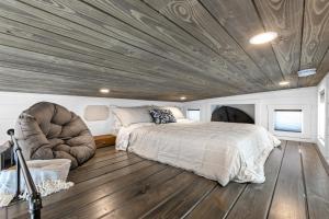 a bedroom with a bed and a reclining chair at Red Door Tiny Home Lewis Ranch in Lindsay