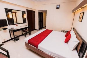 a bedroom with a bed and a desk with a computer at Garden Hotel Panvel in Navi Mumbai