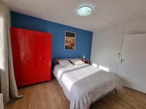 um quarto com uma cama vermelha e paredes azuis em La Bulle em Liévin